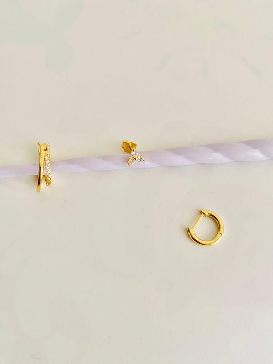 Gold hoop earrings on a light pink background