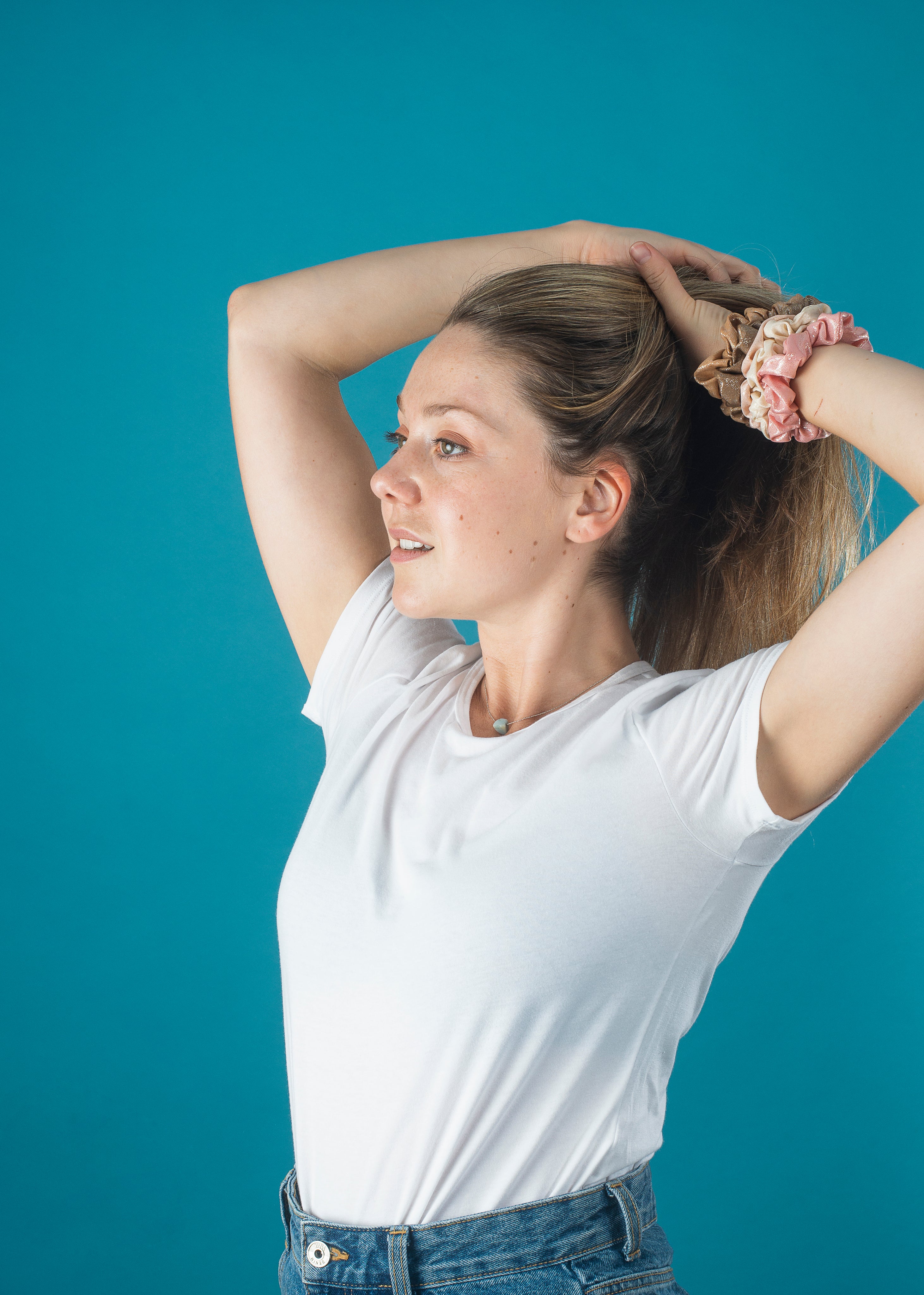 woman-in-a-white-shirt-puts-her-hair-up-with-scrunchies